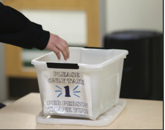 A student reaches into an empty after-school snack-bin in the Commons.